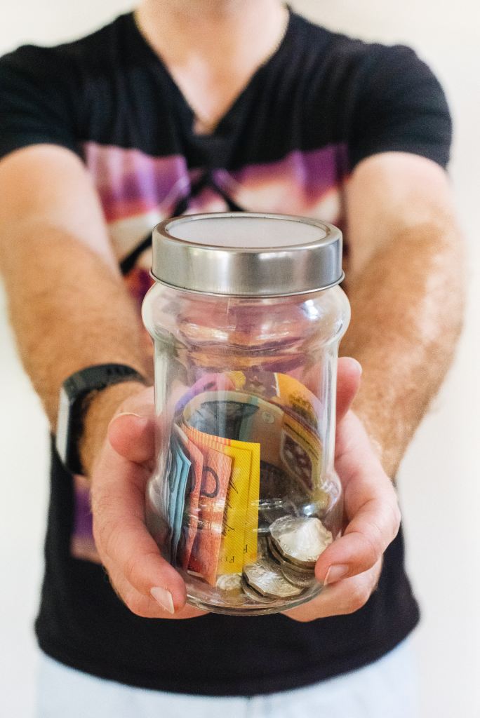 Person holds a jar of Australian notes and coins