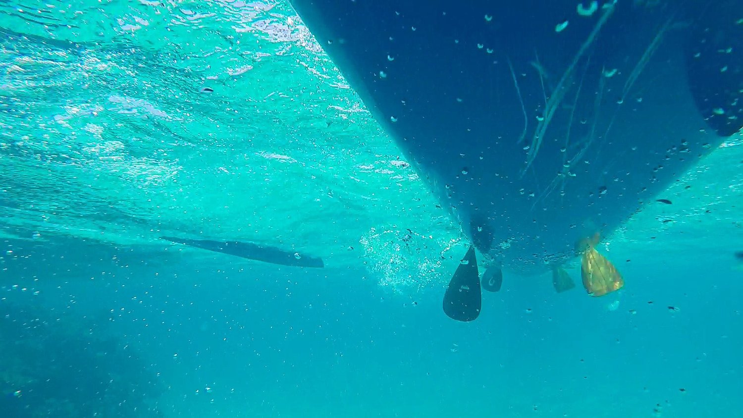 Underwater perspective of outrigger canoes and paddlers' blades